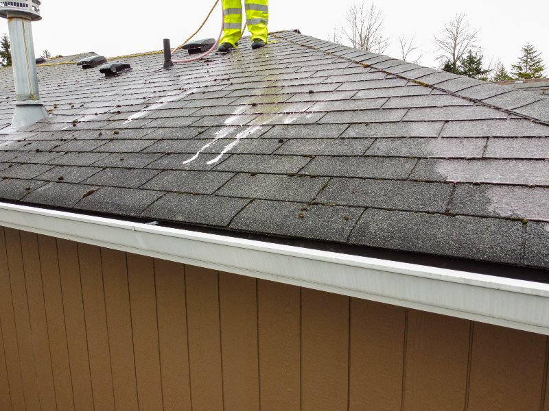 up close view of roof with professional in yellow cleaning suit cleaning it