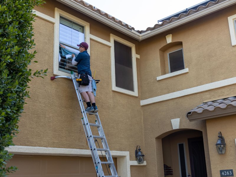 professional standing on a ladder cleaning exterior windows