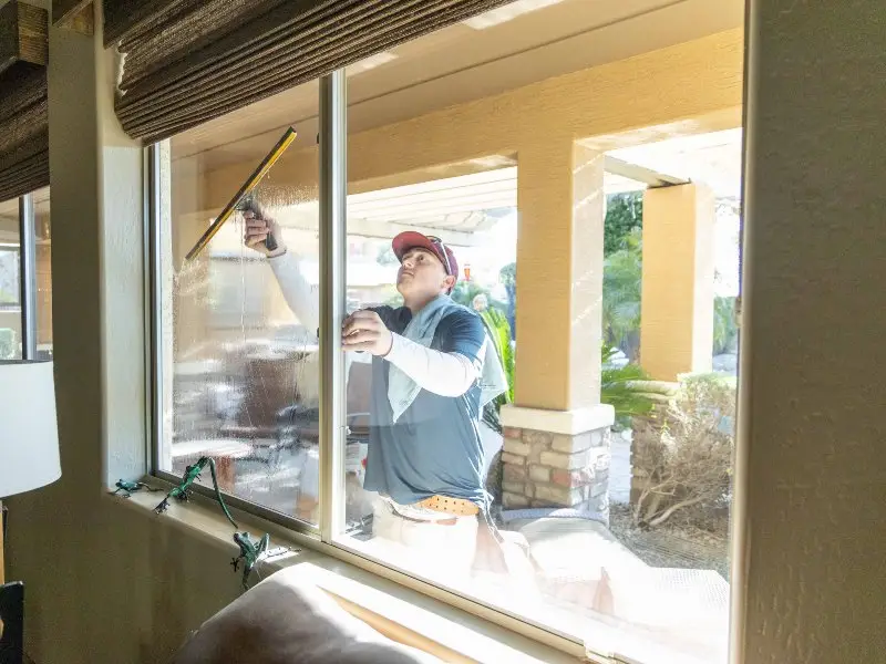 professional cleaning exterior window of brown home